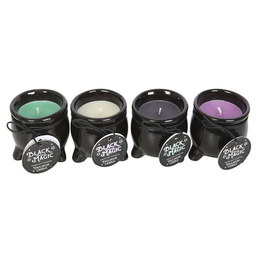 Four black candle holders with lit candles inside on a white background
