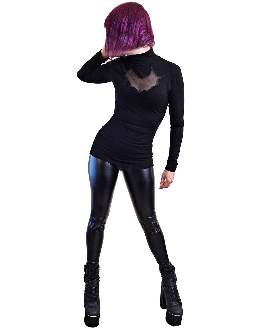 Person wearing a black long-sleeve top and shiny black leggings on a white background