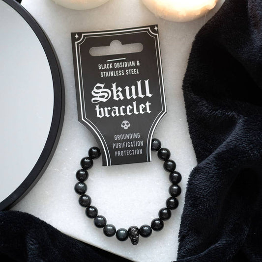 Black skull bracelet on a white surface with packaging labeled 'Skull bracelet'.