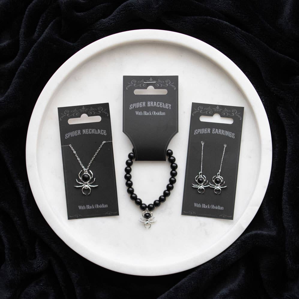 Spider-themed jewelry set on a white plate with black packaging
