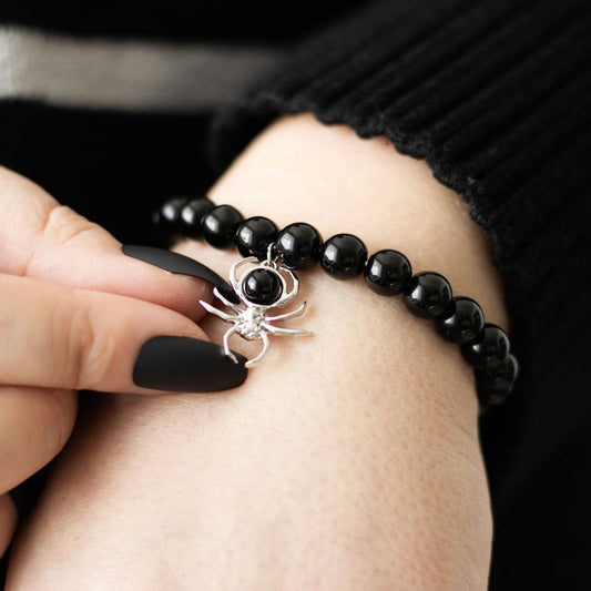 Black beaded bracelet with a spider charm on a person's wrist.