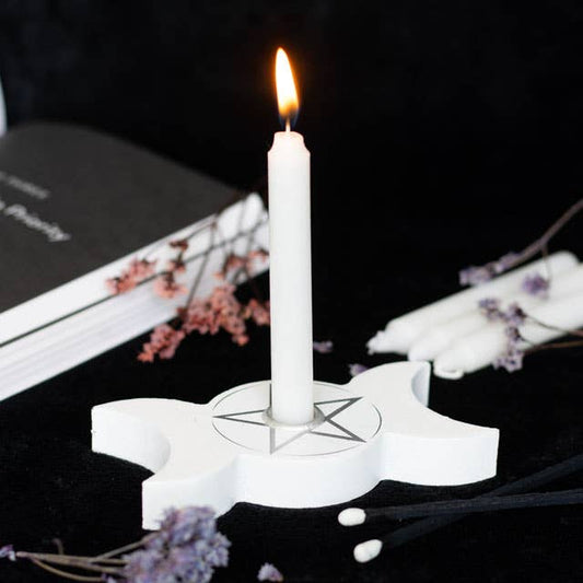 White candle on a star-shaped holder with a black background